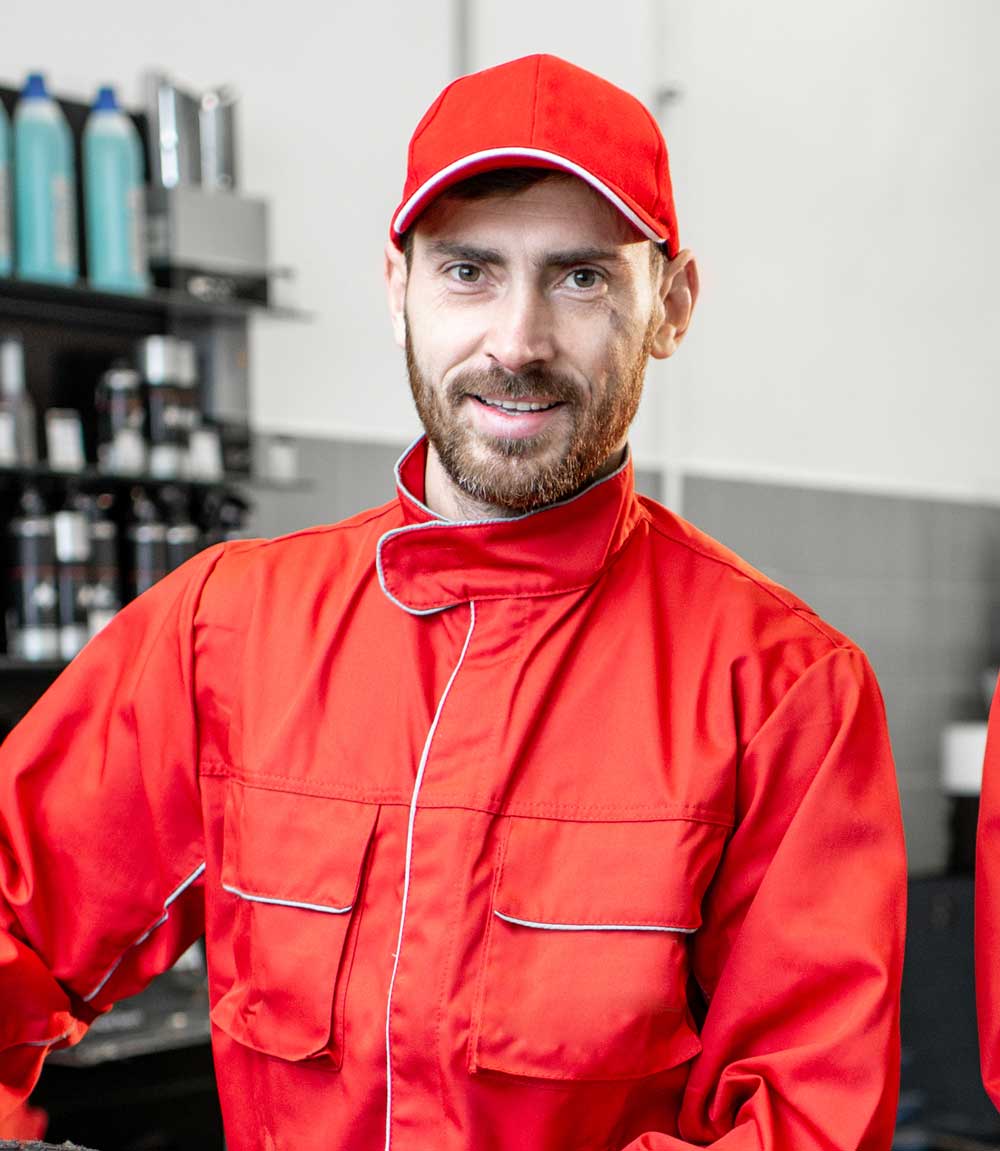 Skilled technician in red uniform and cap, smiling confidently, representing USA Garage Door Repair Naples' commitment to quality service and professionalism.