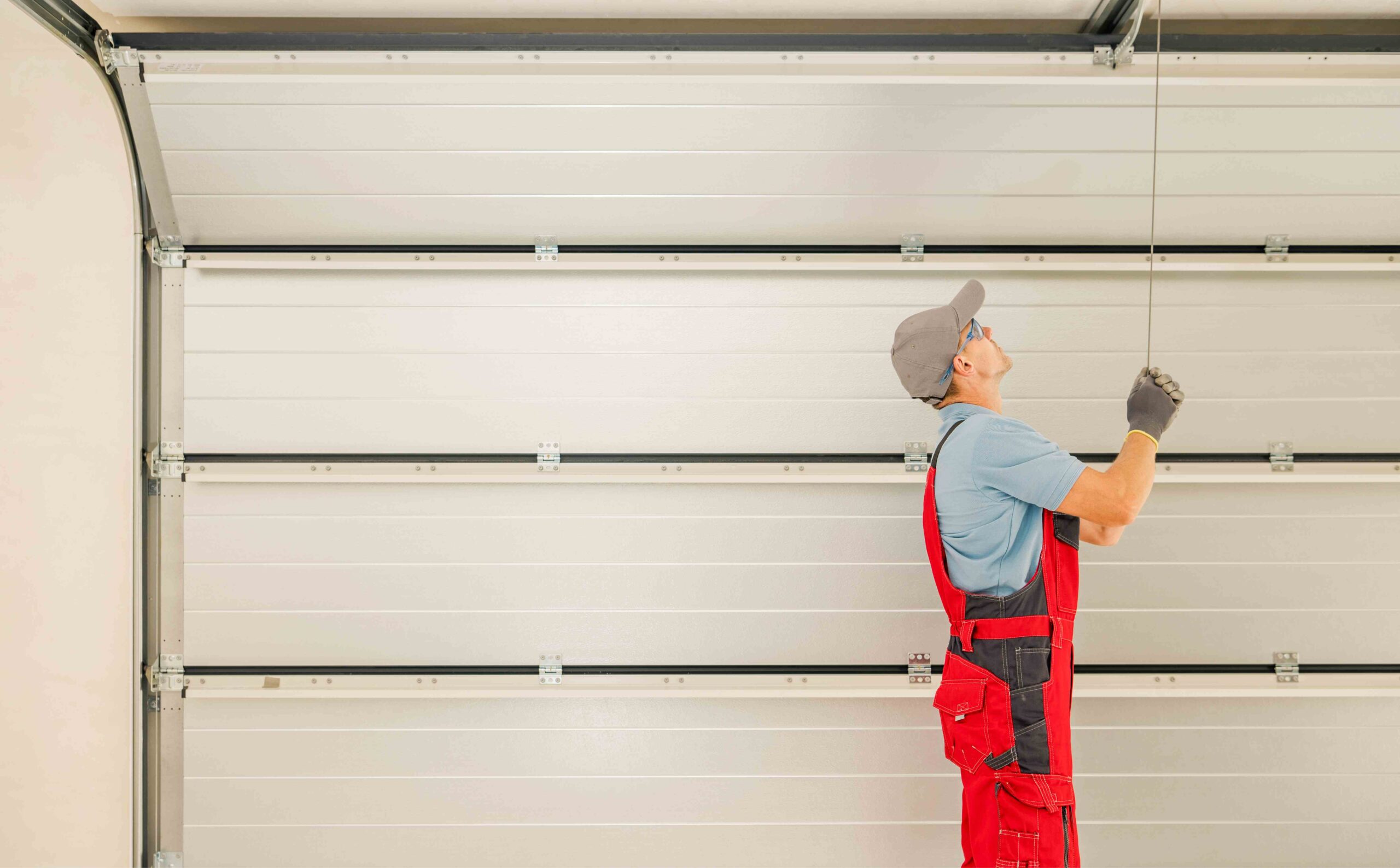 Professional technician in red overalls performing garage door installation in Fort Myers, ensuring reliable service and quality repairs.